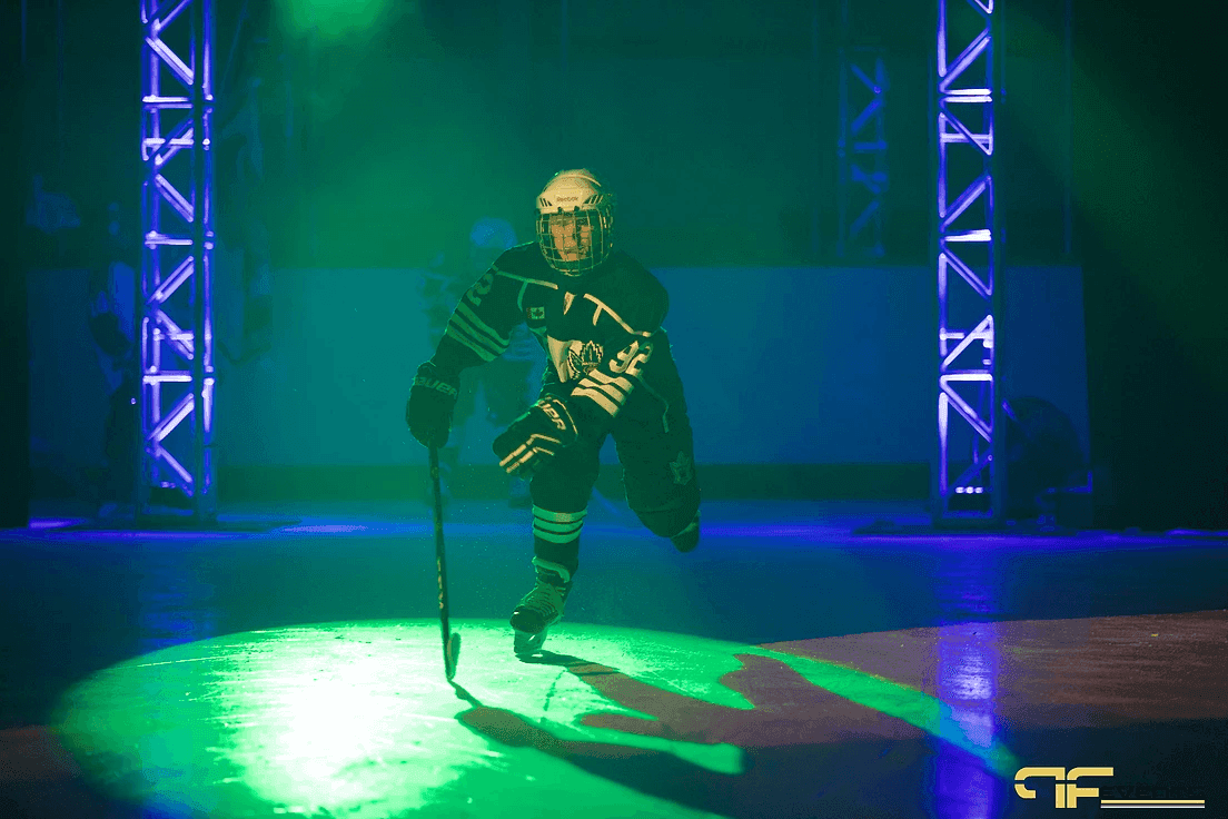 Player skating into a green spotlight between blue-lit truss towers