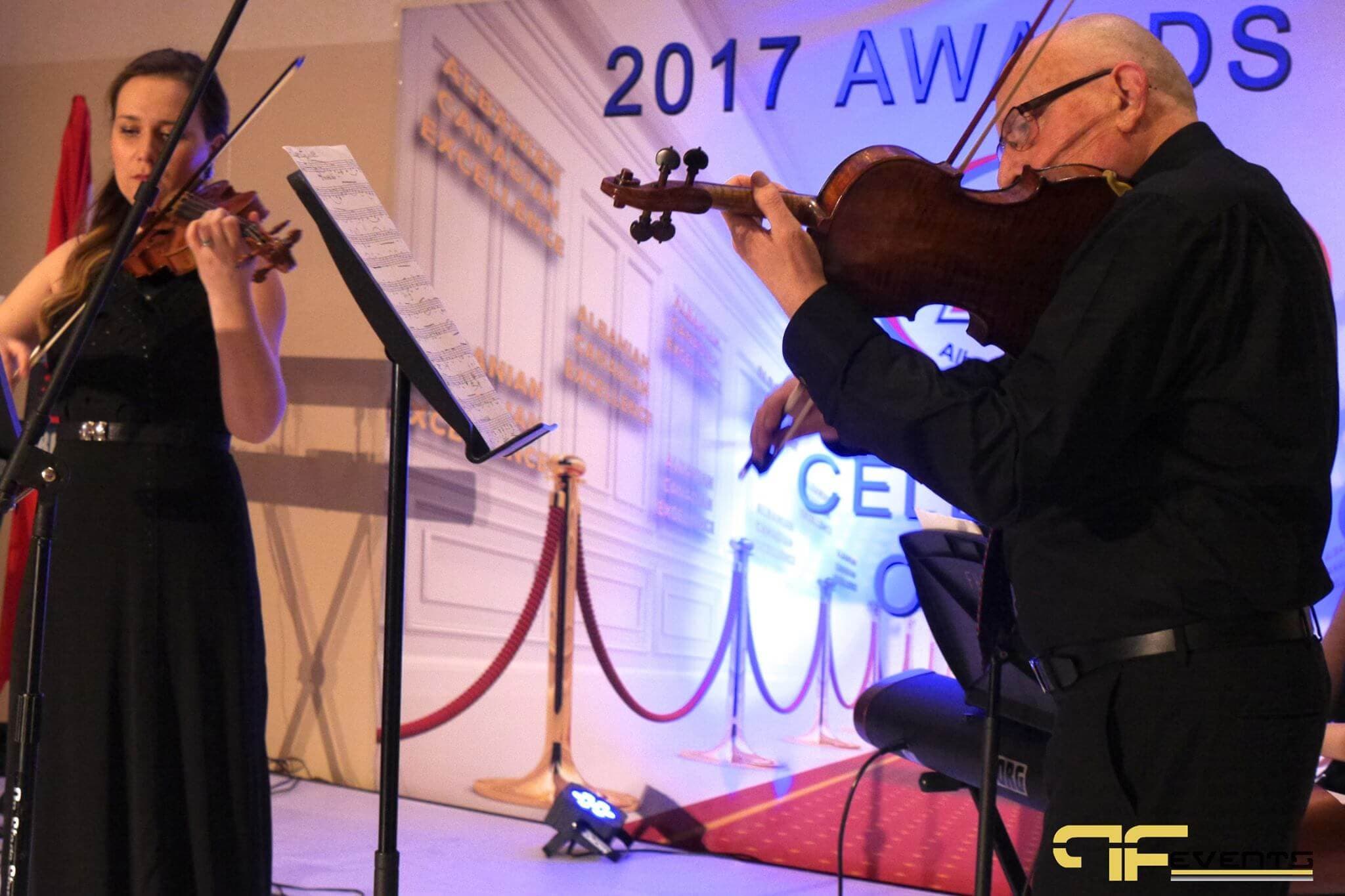 Two violinists performing in front of the 2017 Awards Gala backdrop