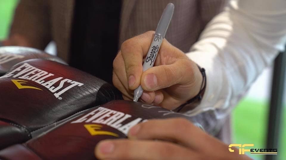 Signing Everlast boxing gloves with a silver marker