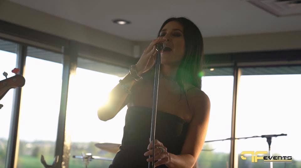 Singer at the mic, backlit by clubhouse windows