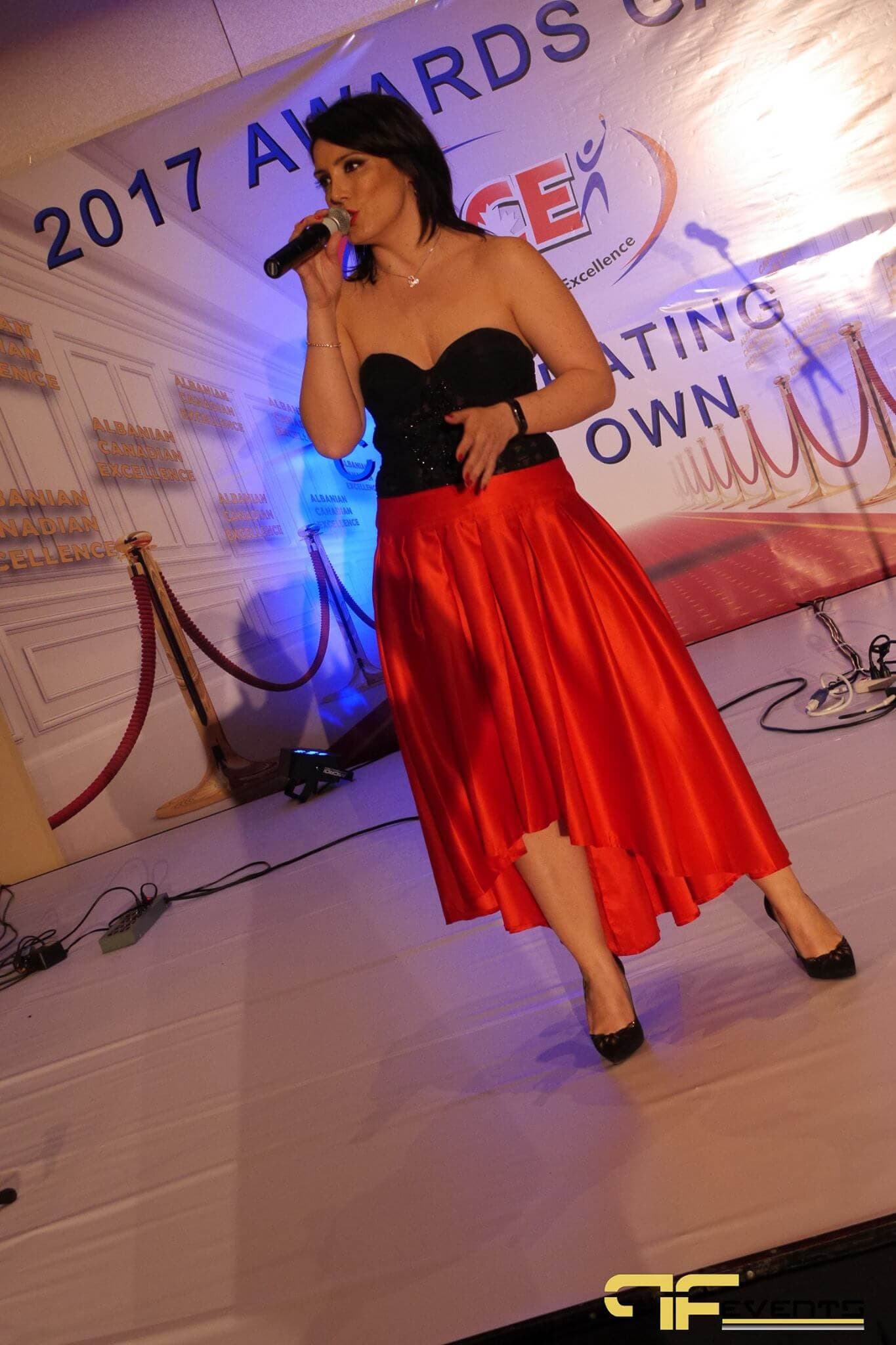 Singer in a red skirt performing in front of the 2017 Awards Gala backdrop