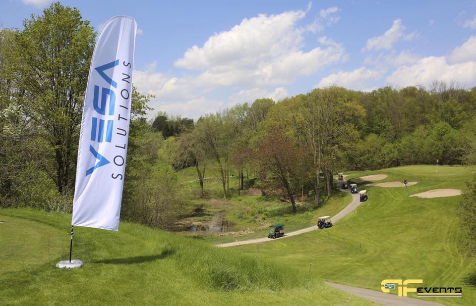 Sponsor feather flag on a tee as golf carts roll down the fairway