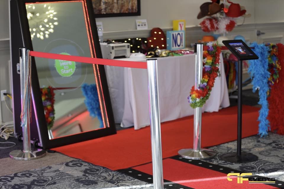 Photo booth with red carpet, stanchions, tablet kiosk and props