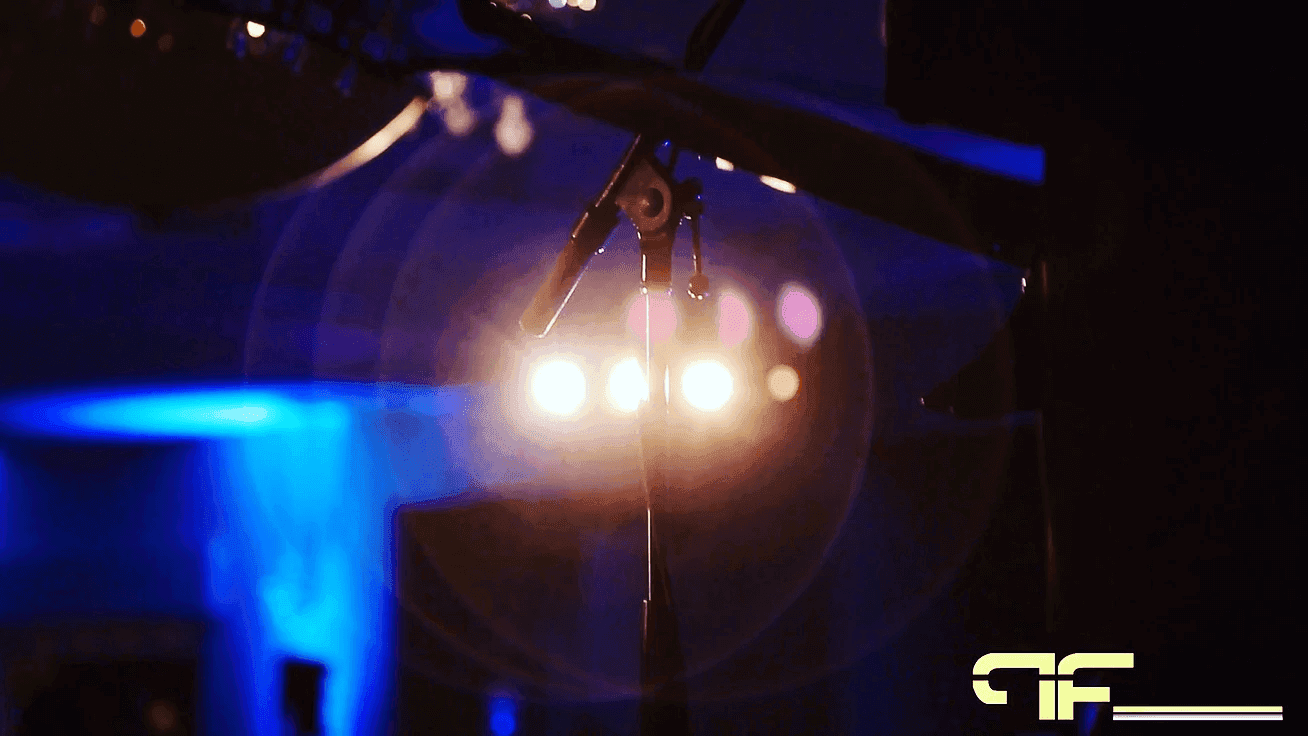 Microphone on a stand silhouetted against stage backlight and blue wash