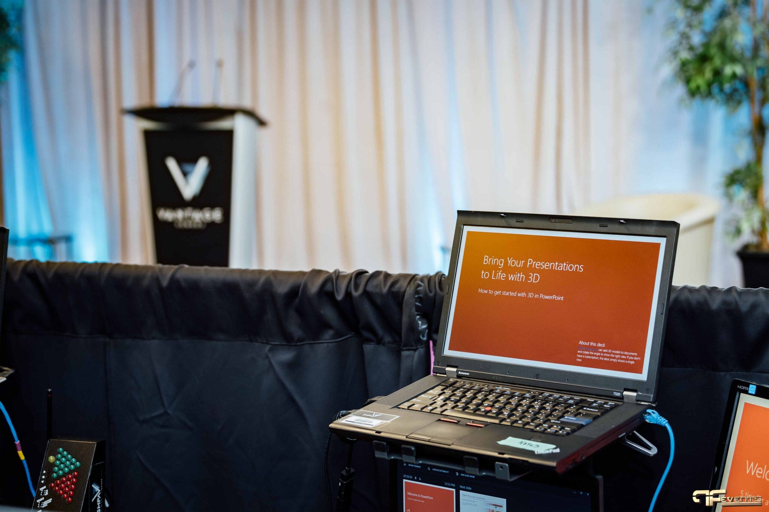 Presentation laptop in front of the podium and uplit drape