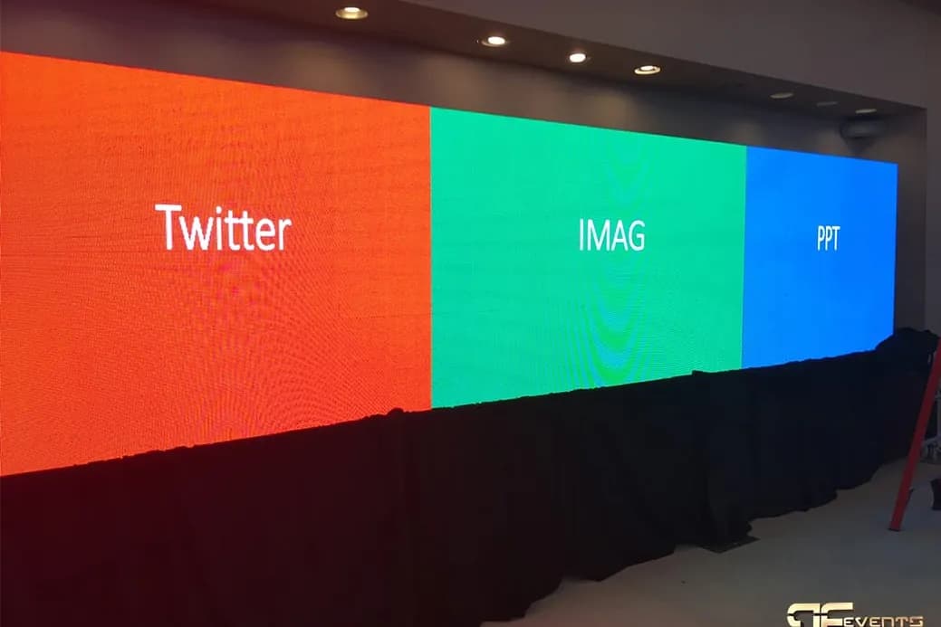 Wide LED video wall split into three content zones for social media, IMAG, and slides, with the room lights on during setup