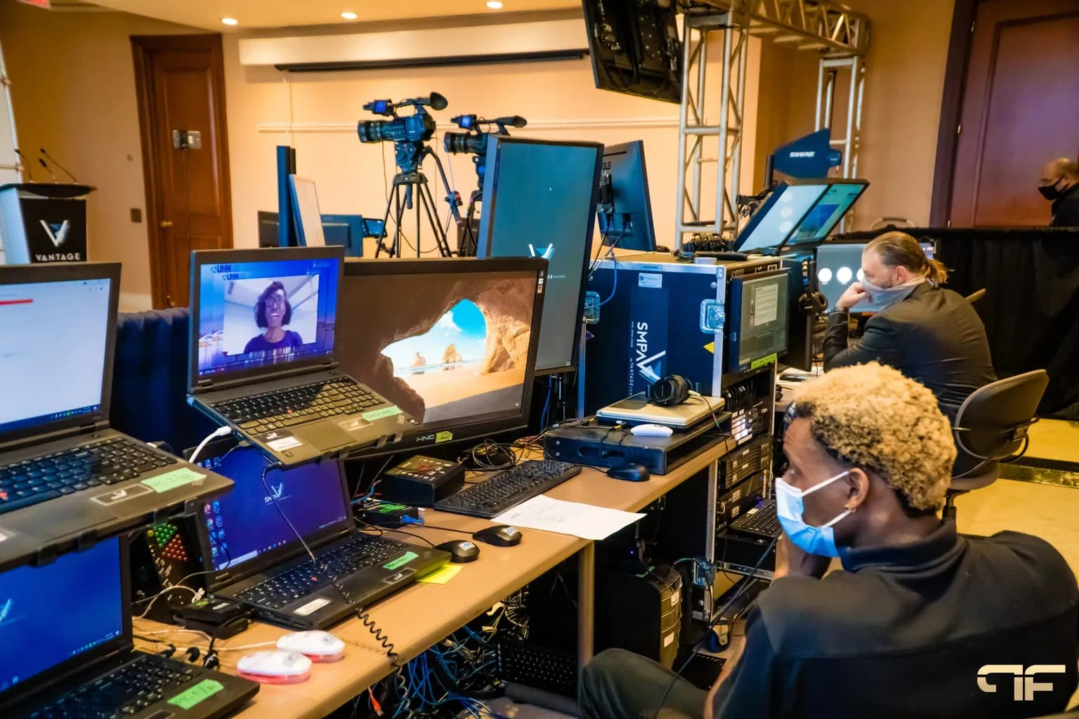 Production crew at a control position with laptops, video monitors, and cameras during a corporate session